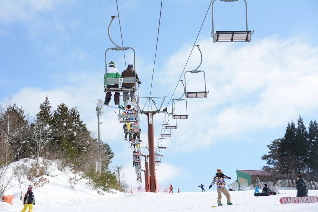 Chairlift carrying skiers up a slope on a blue sky day